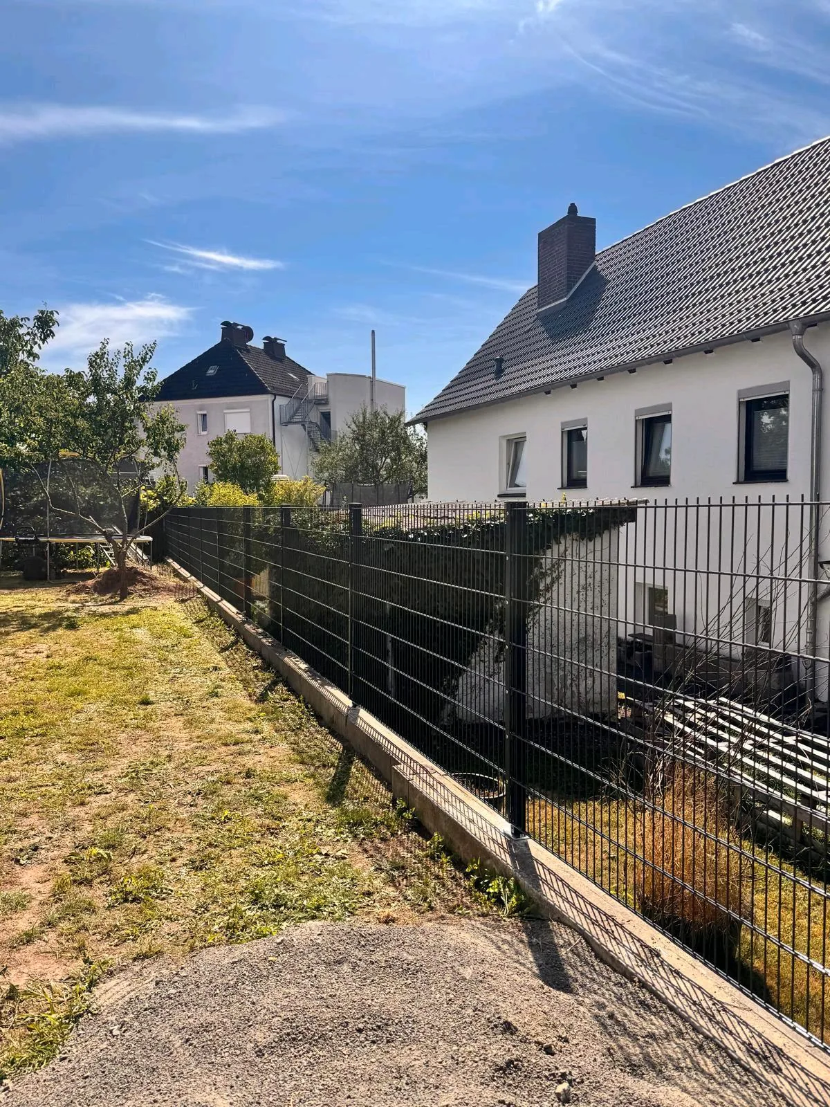 Doppelstabmattenzaun auf einem Betonsockel entlang eines Hausgartens